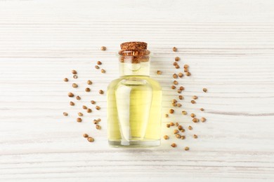 Coriander essential oil and seeds on wooden table, top view