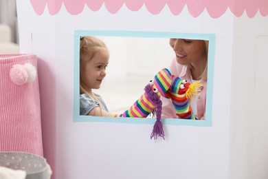 Photo of Mother and daughter performing show in puppet theatre at home