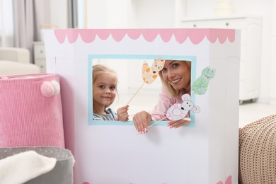 Mother and daughter performing show in puppet theatre at home