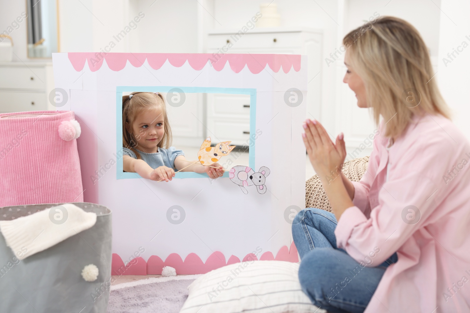 Photo of Puppet theatre. Girl performing show with toy to her mother at home