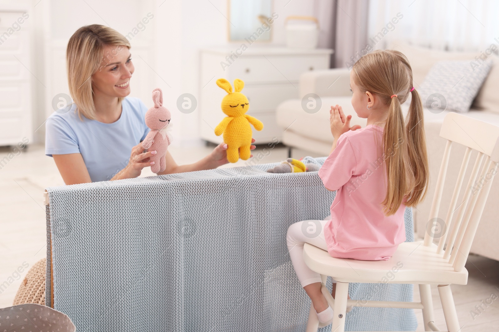 Photo of Puppet theatre. Smiling mother and daughter performing show at home