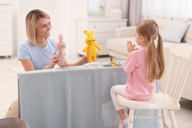 Puppet theatre. Smiling mother and daughter performing show at home