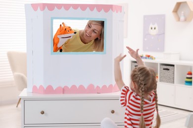 Puppet theatre. Smiling mother performing show with toy to her daughter at home