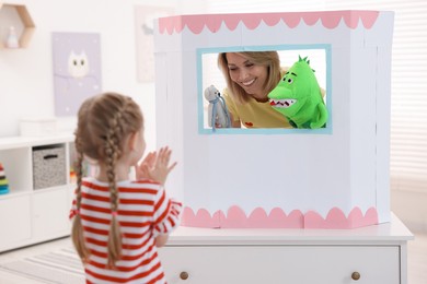 Puppet theatre. Smiling mother performing show with toys to her daughter at home