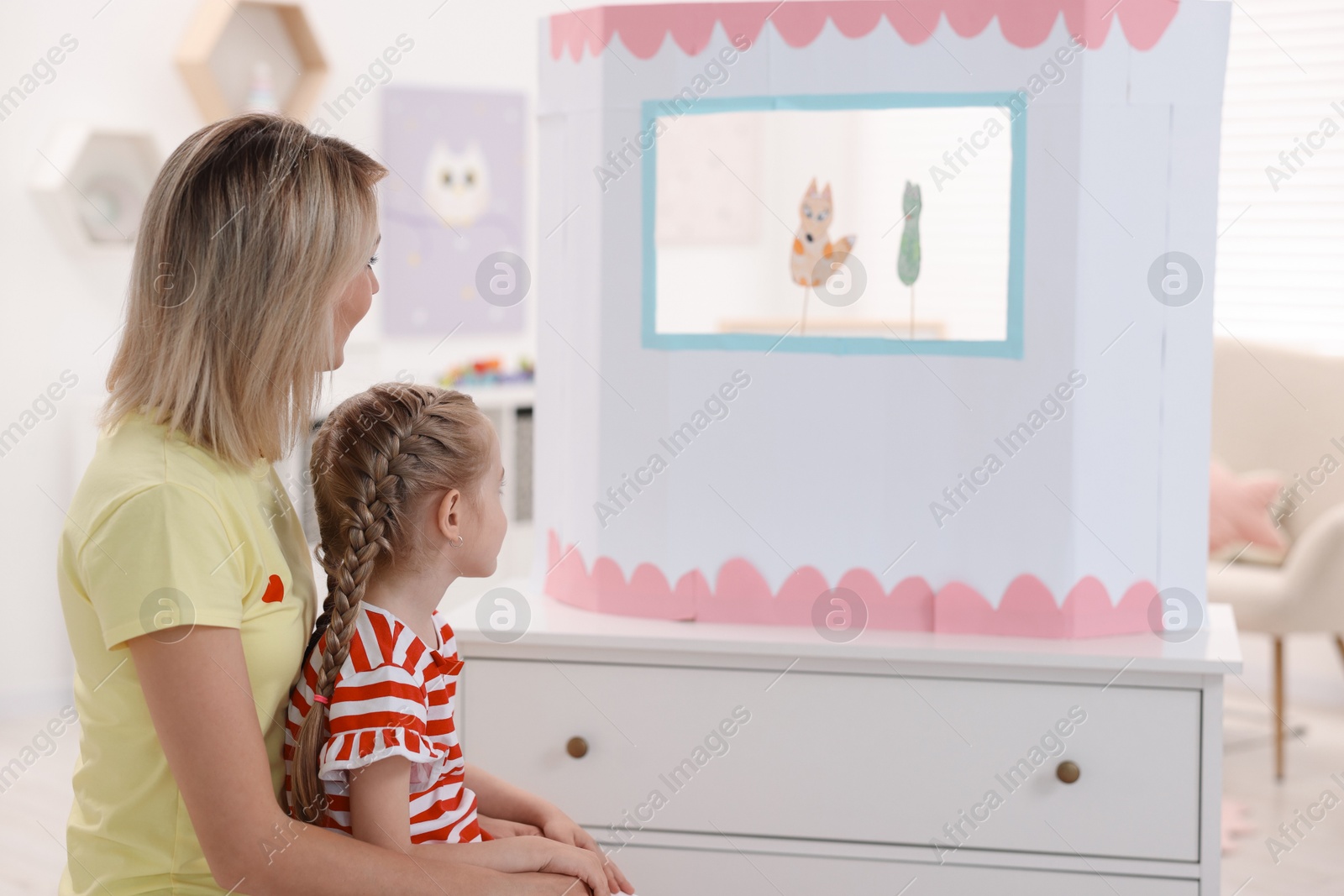 Photo of Mother and daughter watching puppet theatre at home