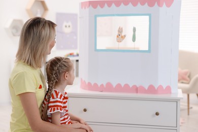Photo of Mother and daughter watching puppet theatre at home