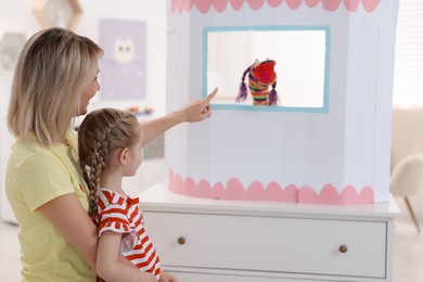 Photo of Mother and daughter watching puppet theatre at home