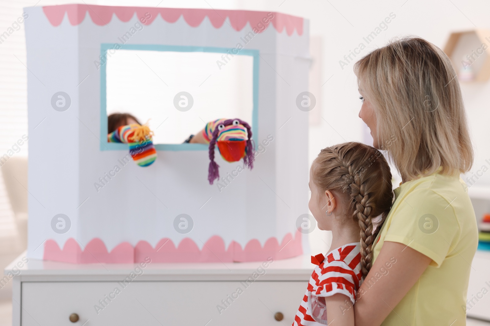 Photo of Mother and daughter watching puppet theatre at home