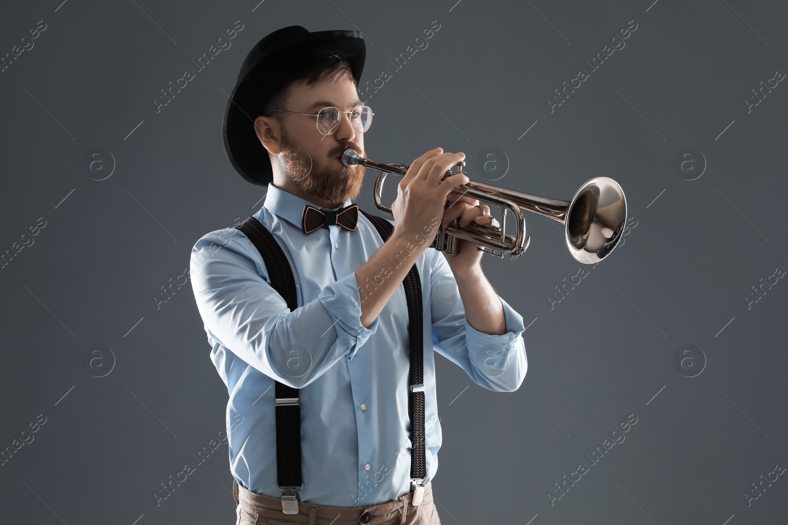 Photo of Handsome musician playing trumpet on grey background