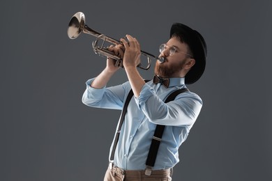 Photo of Handsome musician playing trumpet on grey background