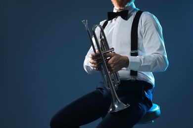 Photo of Professional musician with trumpet on dark background, closeup. Space for text