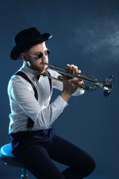 Professional musician playing trumpet on dark background