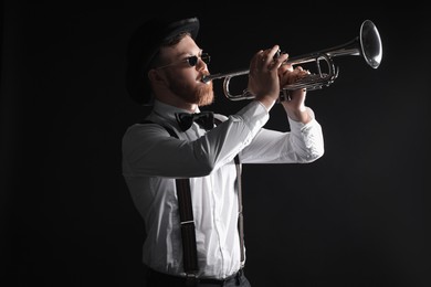 Professional musician playing trumpet on black background