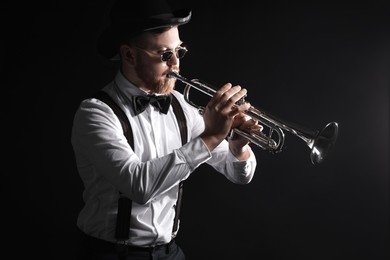 Professional musician playing trumpet on black background