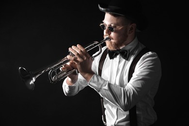 Professional musician playing trumpet on black background