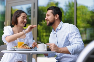 Photo of Happy couple having breakfast in outdoor cafe