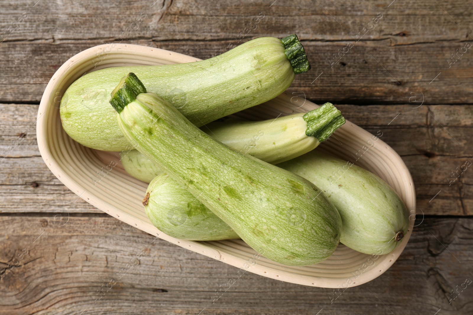 Photo of Raw green zucchinis on wooden table, top view