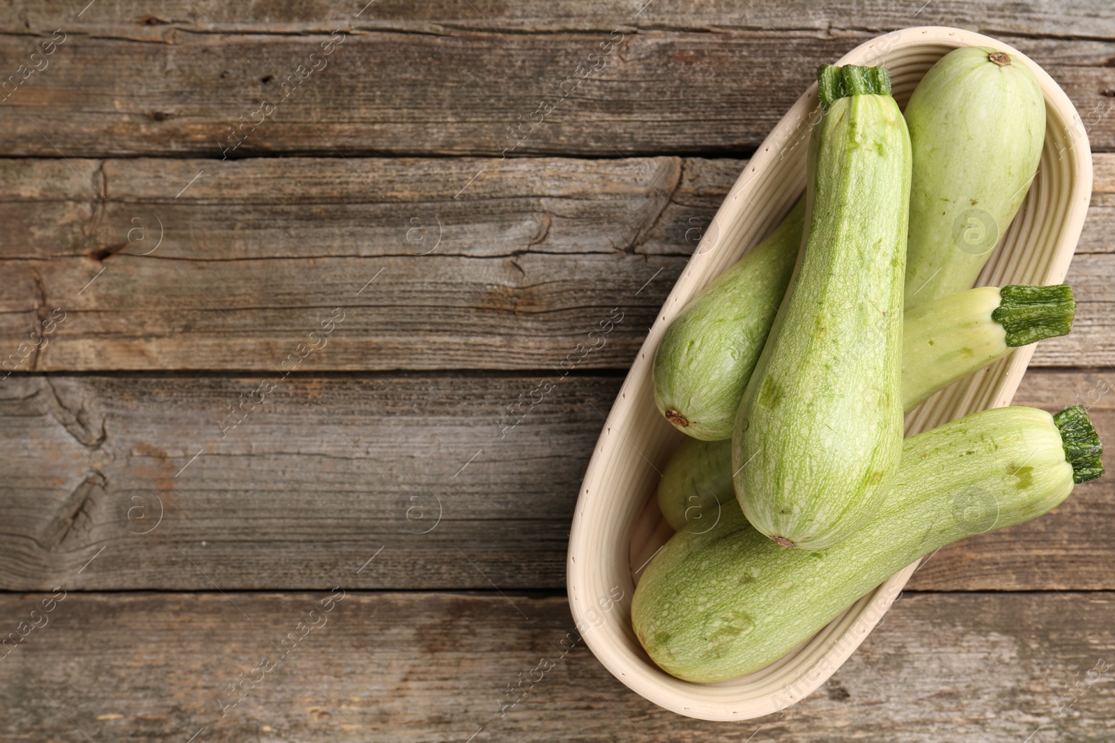 Photo of Raw green zucchinis on wooden table, top view. Space for text