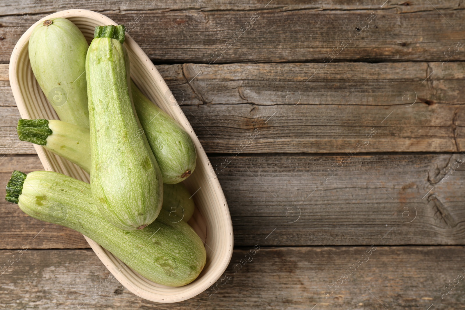 Photo of Raw green zucchinis on wooden table, top view. Space for text