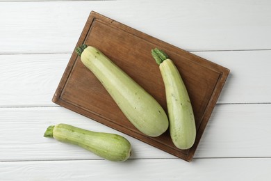 Photo of Raw green zucchinis on white wooden table, top view