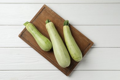 Photo of Raw green zucchinis on white wooden table, top view