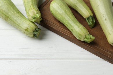 Photo of Raw green zucchinis on white wooden table, space for text