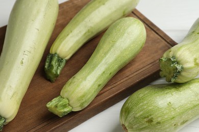 Photo of Raw green zucchinis on white wooden table, closeup