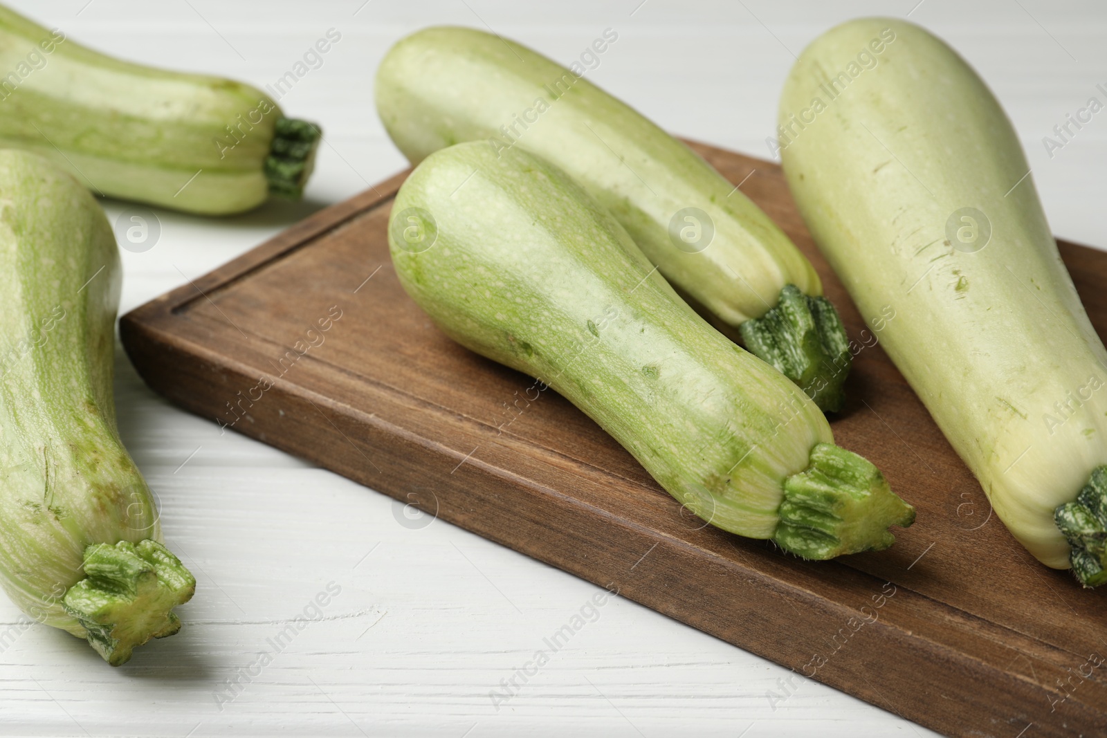 Photo of Raw green zucchinis on white wooden table, closeup