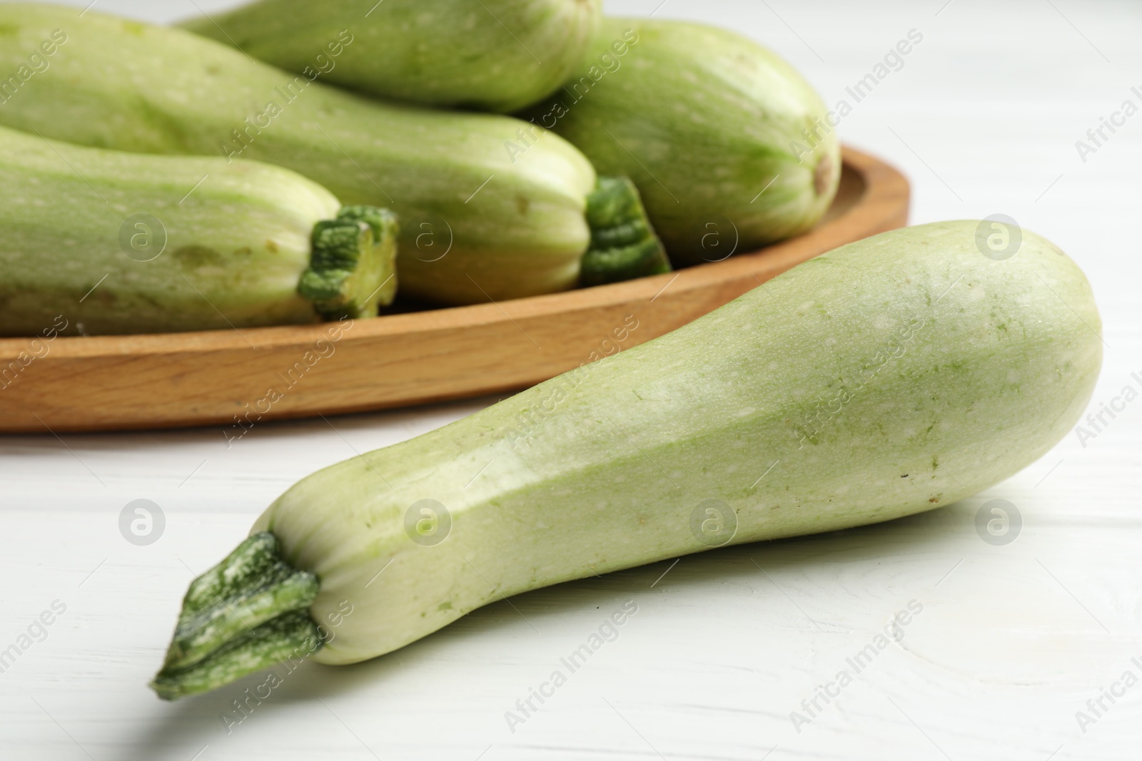 Photo of Raw green zucchinis on white wooden table, closeup