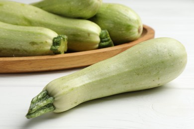 Photo of Raw green zucchinis on white wooden table, closeup