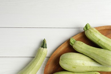 Photo of Raw green zucchinis on white wooden table, top view. Space for text