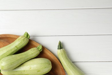 Photo of Raw green zucchinis on white wooden table, top view. Space for text