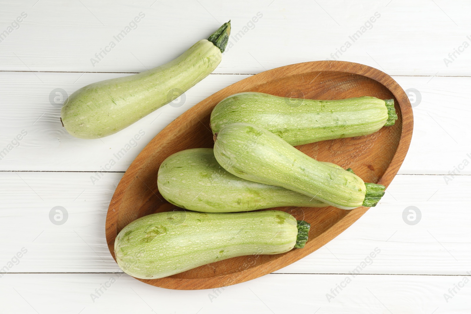 Photo of Raw green zucchinis on white wooden table, top view