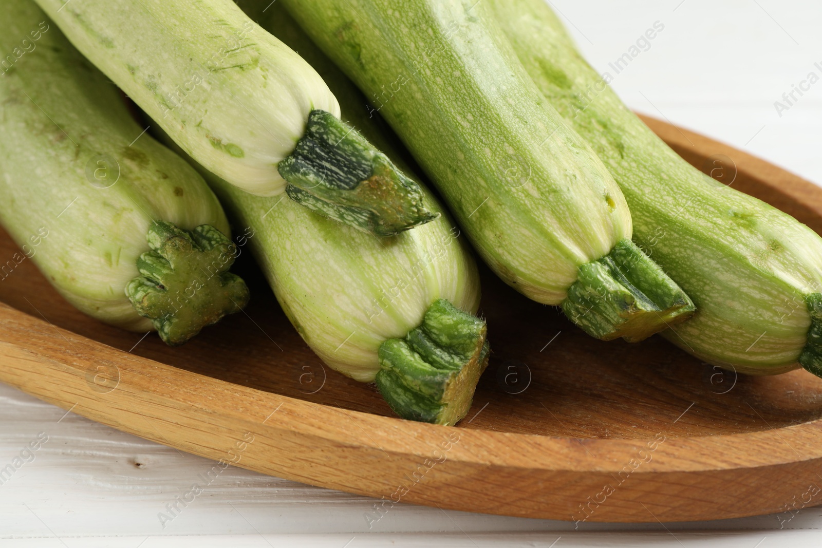 Photo of Raw green zucchinis on white wooden table, closeup