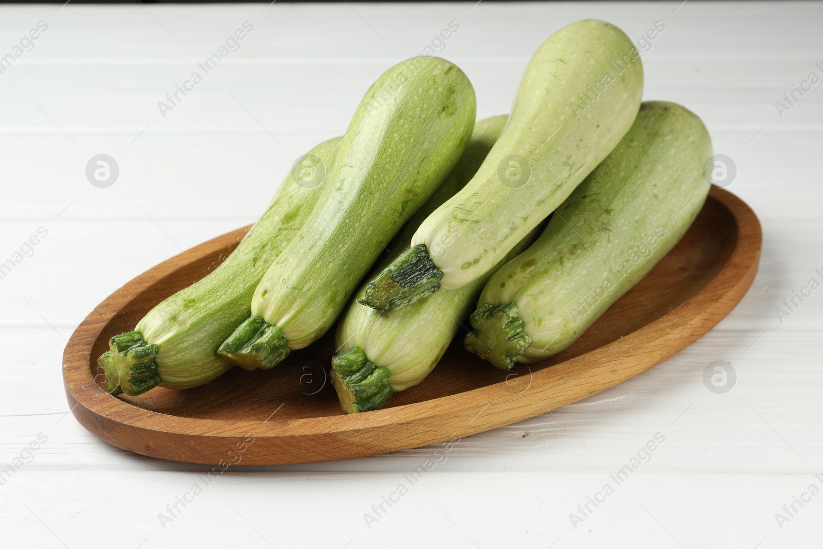 Photo of Raw green zucchinis on white wooden table