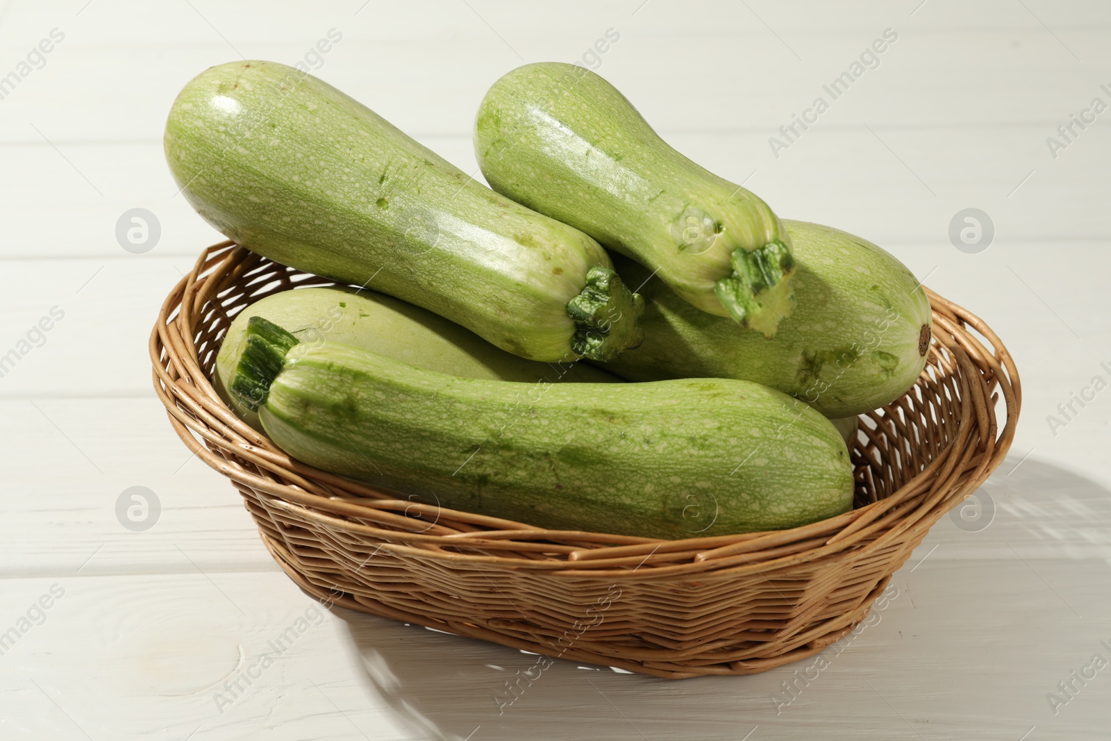 Photo of Raw green zucchinis on white wooden table