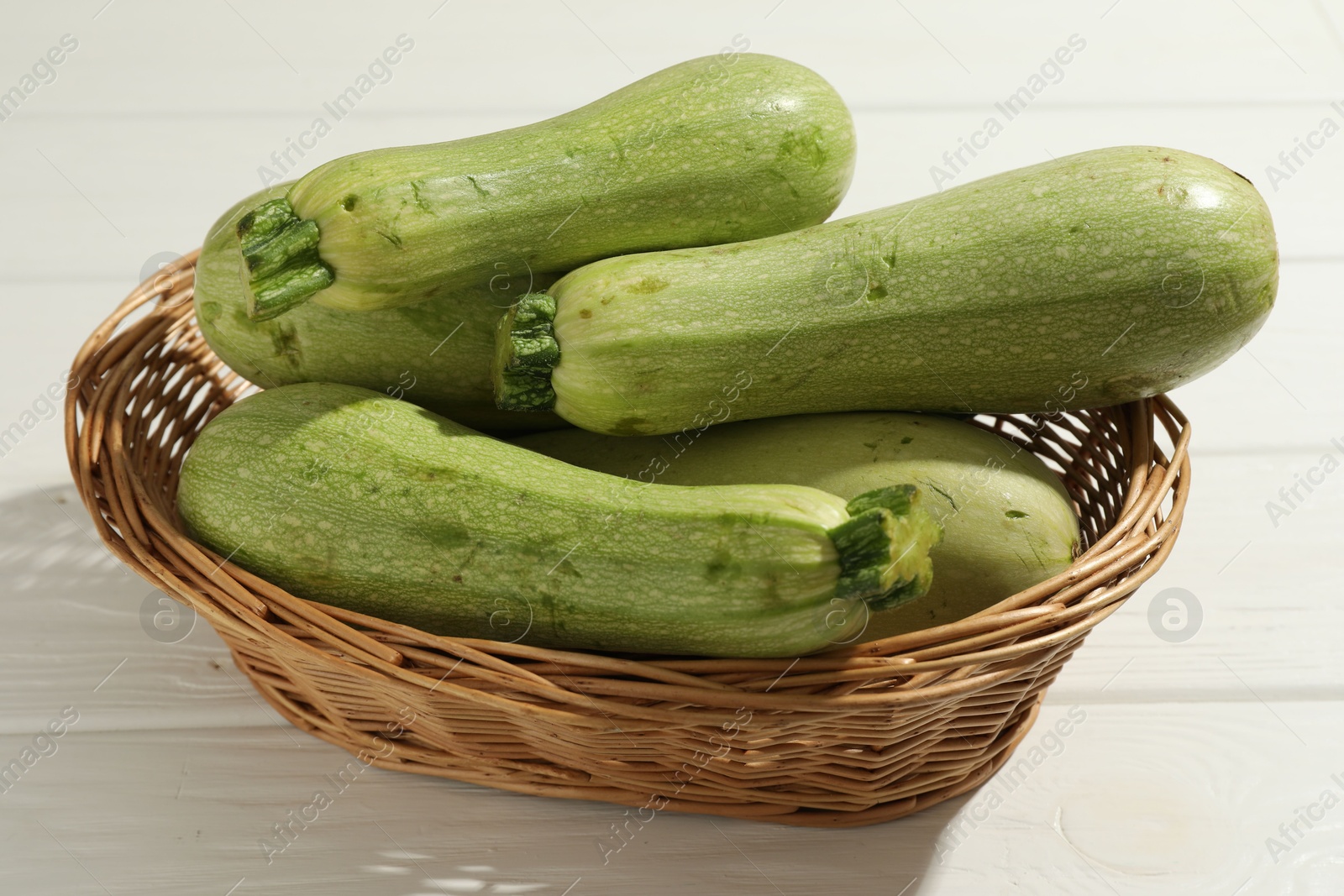 Photo of Raw green zucchinis on white wooden table