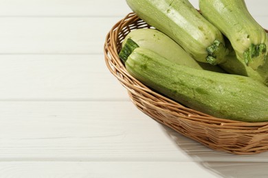 Photo of Raw green zucchinis on white wooden table, closeup. Space for text