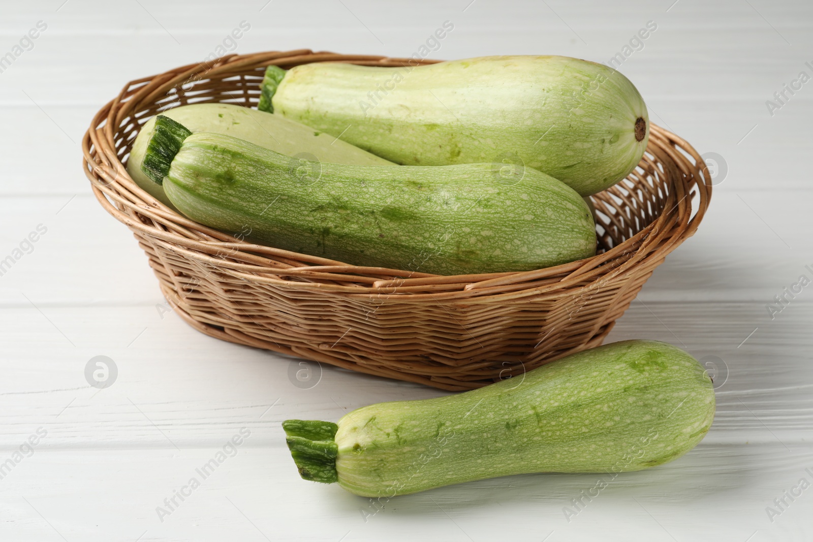 Photo of Raw green zucchinis on white wooden table