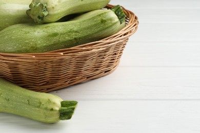 Photo of Raw green zucchinis on white wooden table, closeup. Space for text