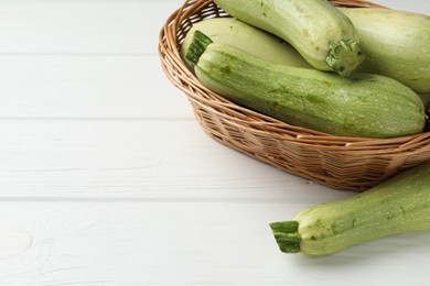 Raw green zucchinis on white wooden table, closeup. Space for text