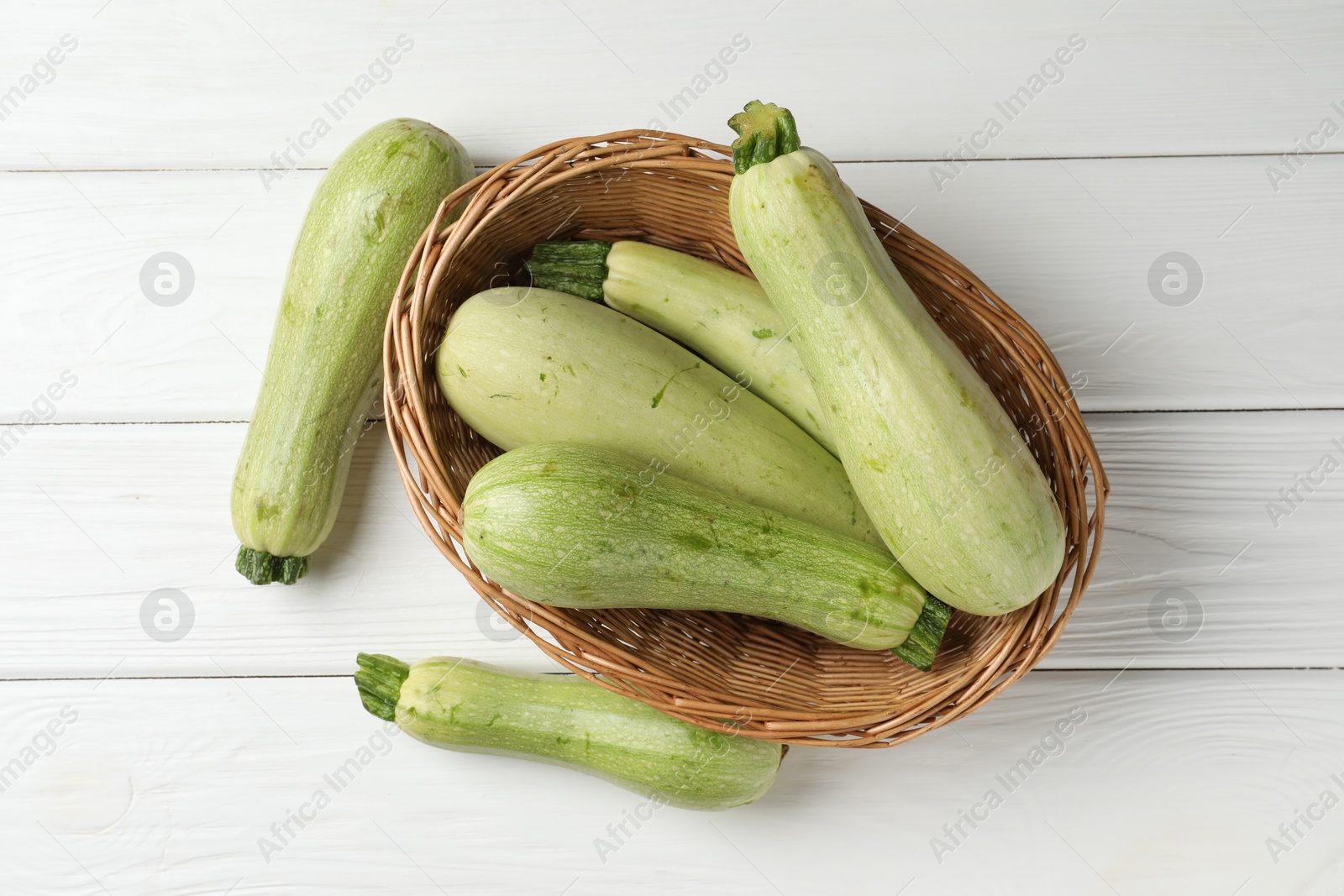 Photo of Raw green zucchinis on white wooden table, top view