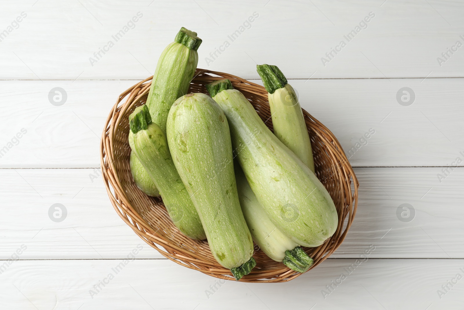 Photo of Raw green zucchinis on white wooden table, top view