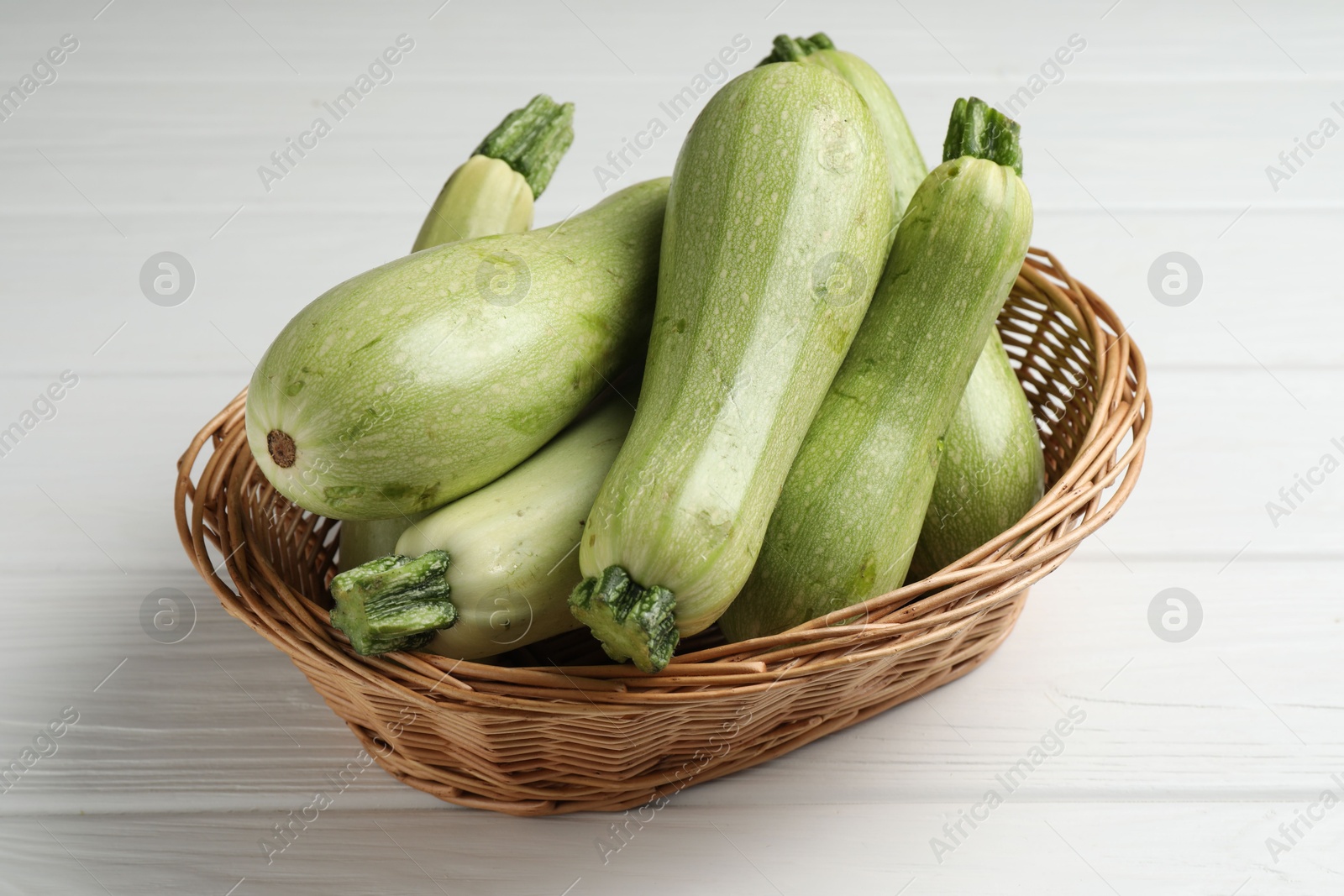 Photo of Raw green zucchinis on white wooden table