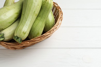 Photo of Raw green zucchinis on white wooden table, space for text