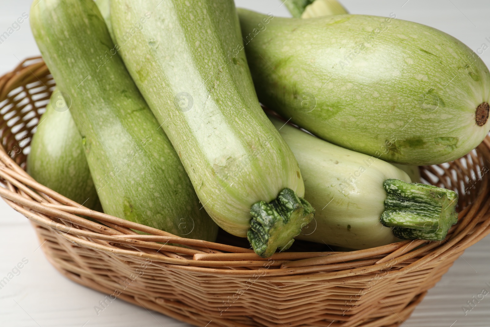 Photo of Raw green zucchinis on white wooden table, closeup