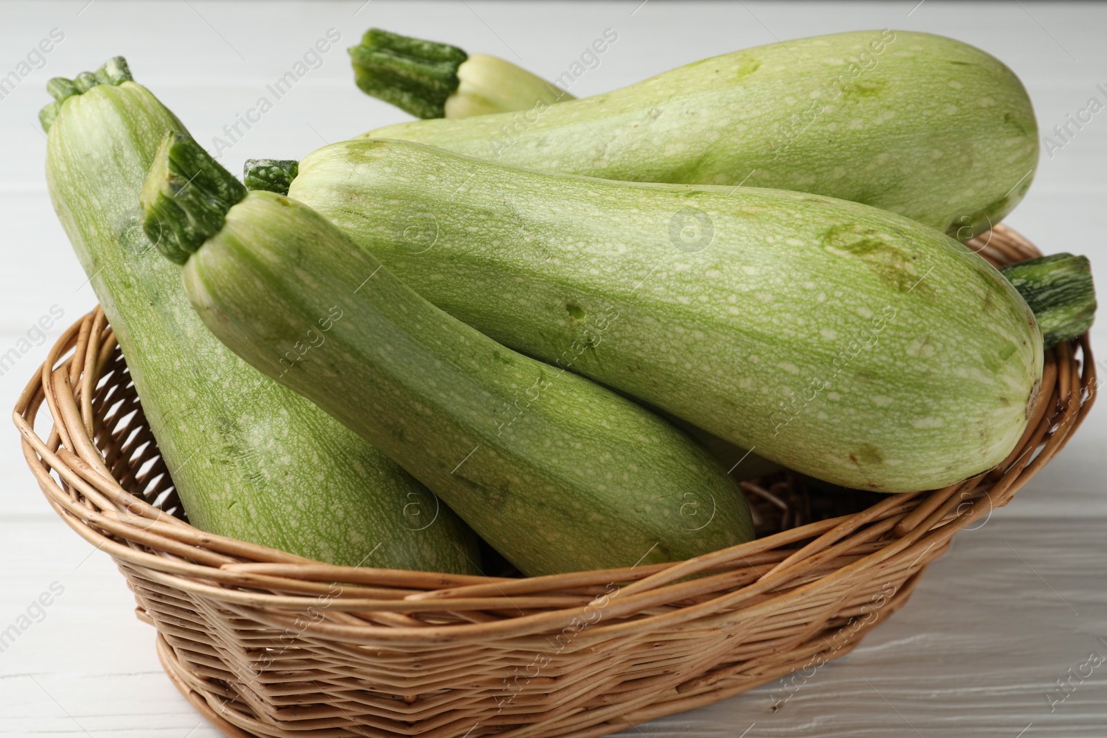 Photo of Raw green zucchinis on white wooden table, closeup