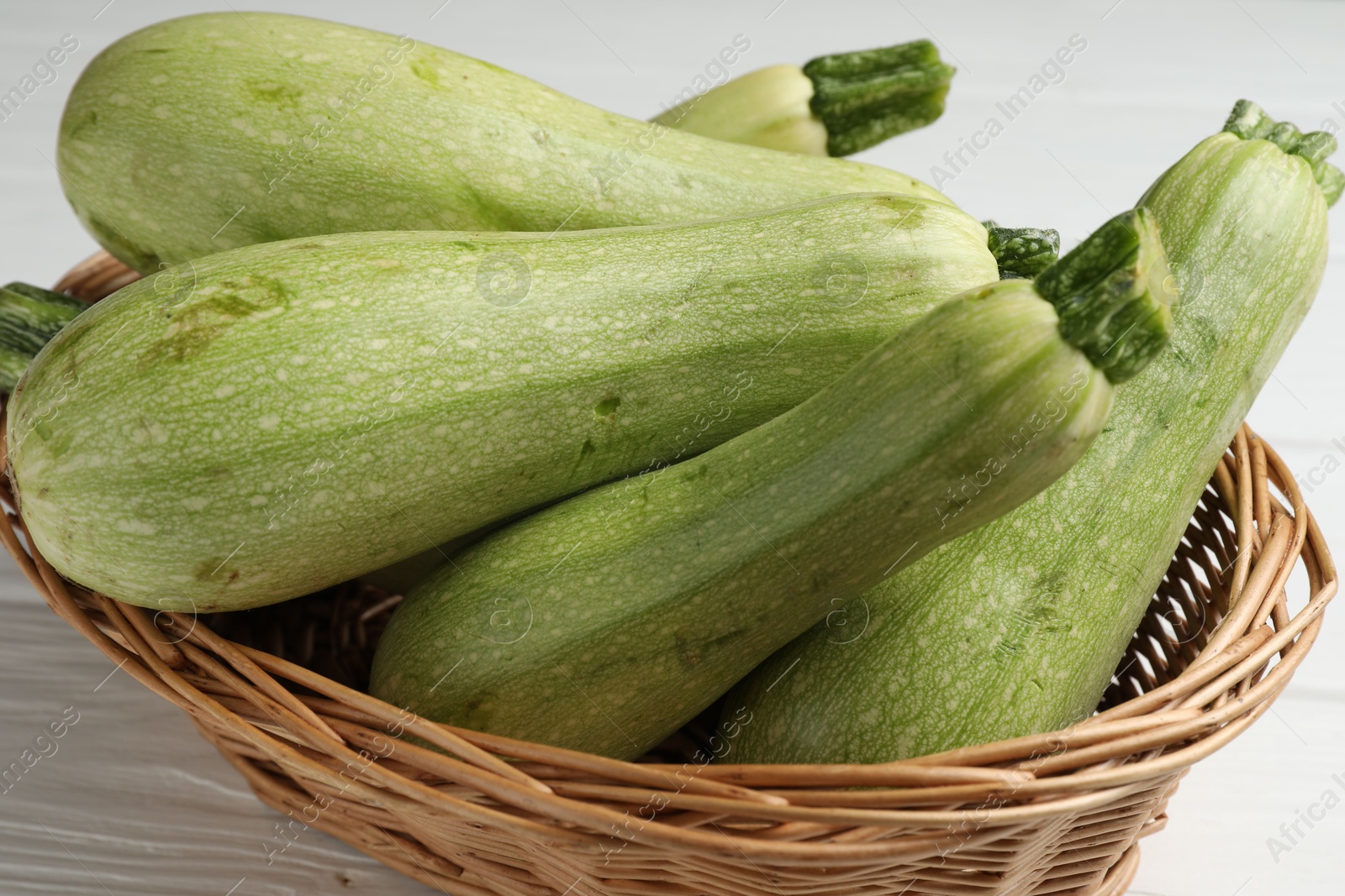 Photo of Raw green zucchinis on white wooden table, closeup