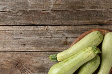 Photo of Raw green zucchinis on wooden table, top view. Space for text