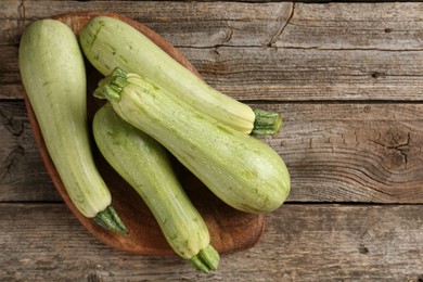 Photo of Raw green zucchinis on wooden table, top view. Space for text